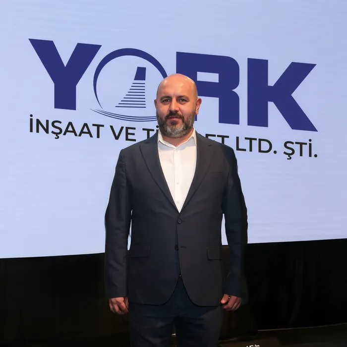 Salih Bal, Gründer von York İnşaat und Bauingenieur (M.Sc.), vor dem Firmenlogo